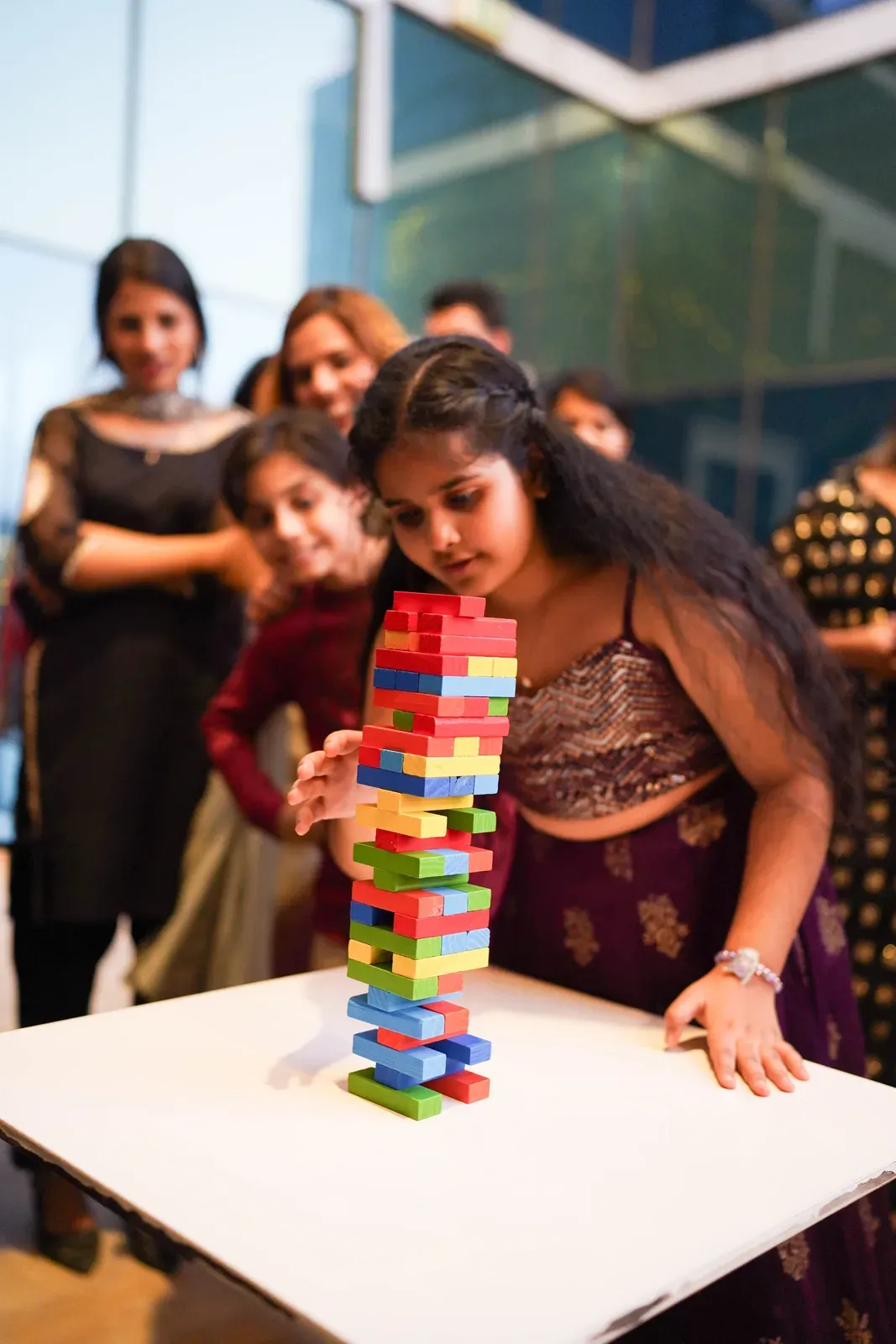 A colleague pulling a block from a tower while the others watch at Diwali.