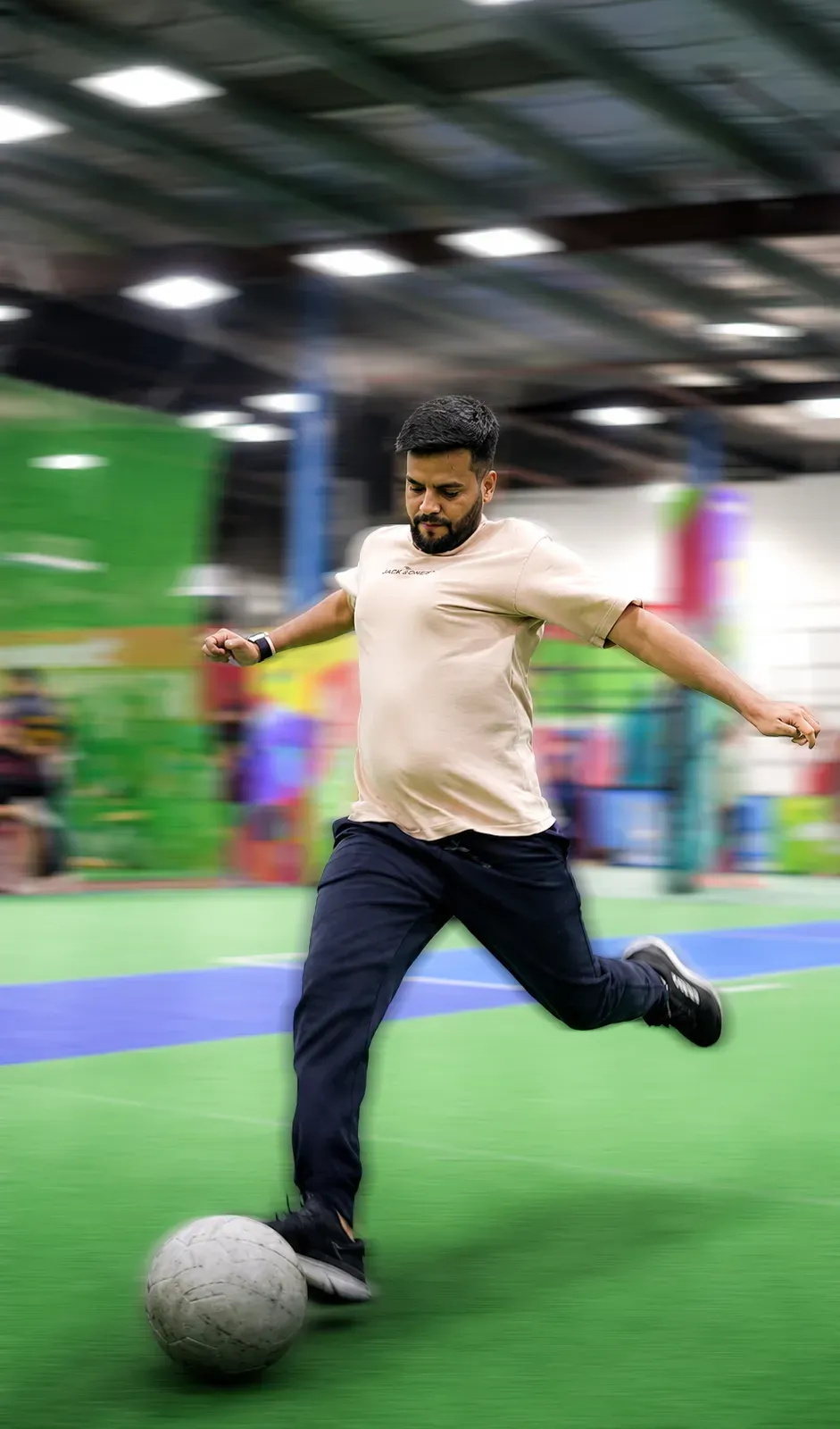 A colleague striking a football on an indoor pitch.